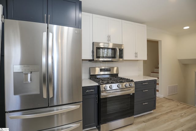 kitchen with white cabinetry, appliances with stainless steel finishes, crown molding, and tasteful backsplash