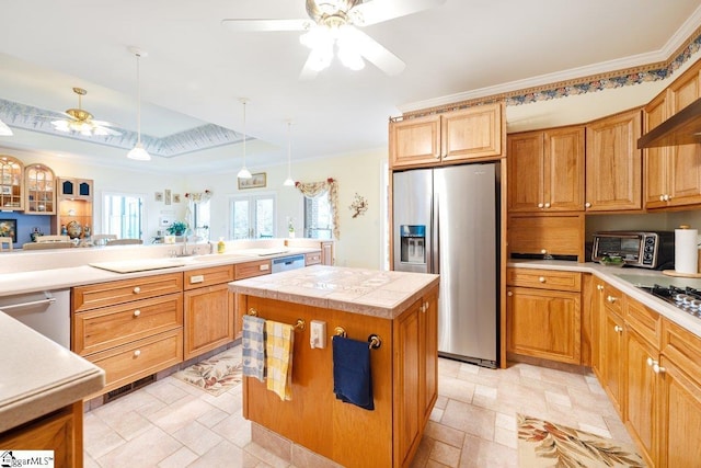 kitchen with ceiling fan, stainless steel appliances, decorative light fixtures, and a center island