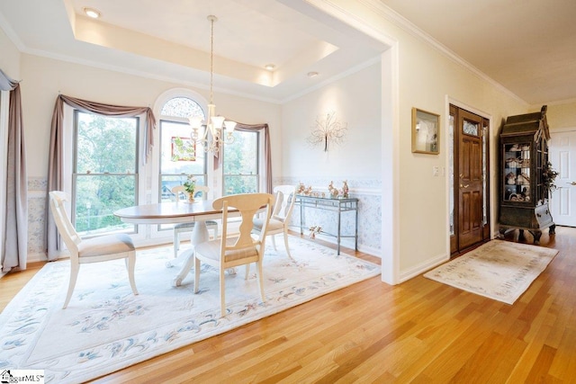 dining area with a chandelier, crown molding, hardwood / wood-style flooring, and a tray ceiling