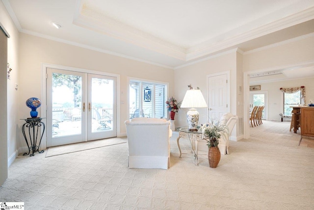 carpeted living room with plenty of natural light, crown molding, a raised ceiling, and french doors