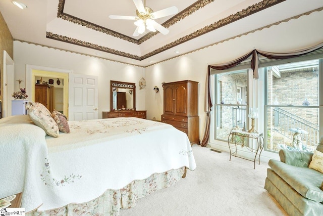 carpeted bedroom with ceiling fan and a raised ceiling