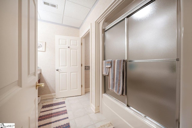 bathroom featuring combined bath / shower with glass door and a paneled ceiling