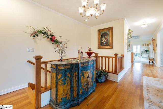 corridor with an inviting chandelier, ornamental molding, and light hardwood / wood-style flooring