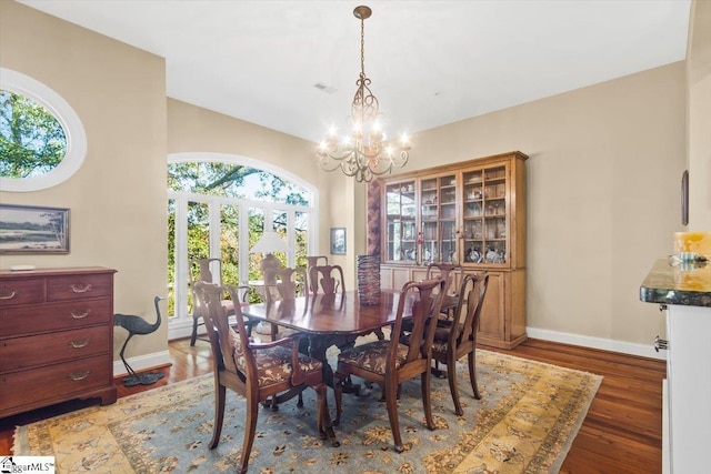 dining area featuring dark wood-type flooring and an inviting chandelier