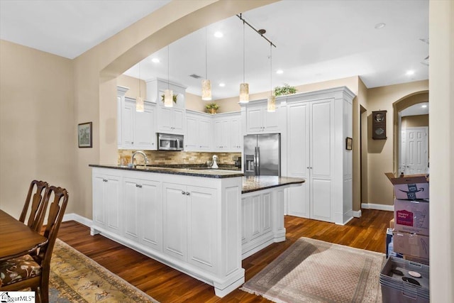 kitchen with decorative light fixtures, backsplash, dark hardwood / wood-style floors, stainless steel appliances, and white cabinets