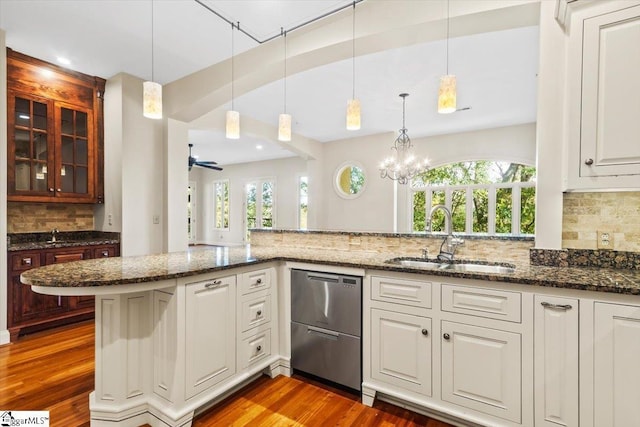 kitchen featuring decorative light fixtures, ceiling fan with notable chandelier, backsplash, and sink