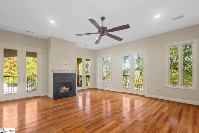 unfurnished living room with ceiling fan, french doors, and light hardwood / wood-style floors