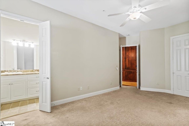 unfurnished bedroom featuring light carpet, ceiling fan, sink, and connected bathroom