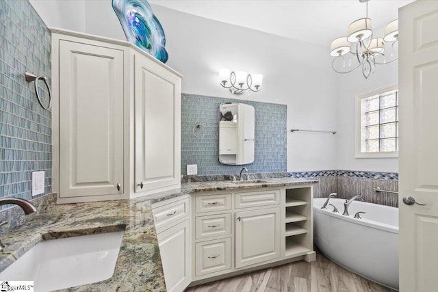 bathroom with a bathing tub, an inviting chandelier, vanity, and tile walls