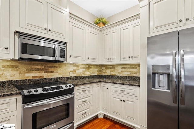 kitchen featuring backsplash, dark stone counters, and stainless steel appliances