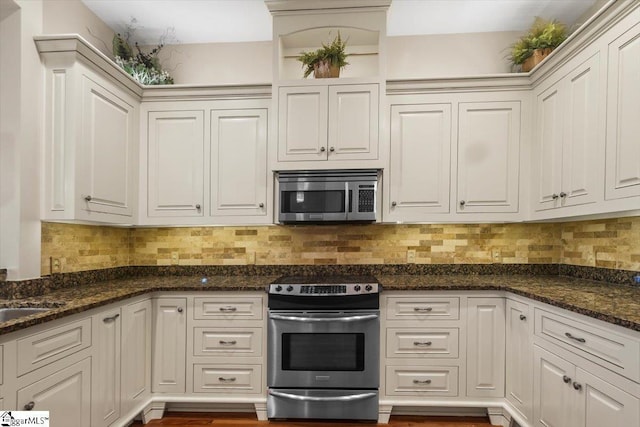 kitchen featuring tasteful backsplash, white cabinets, dark stone counters, and stainless steel appliances