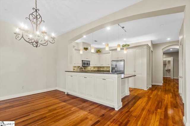 kitchen featuring white cabinetry, dark hardwood / wood-style flooring, stainless steel appliances, hanging light fixtures, and a notable chandelier