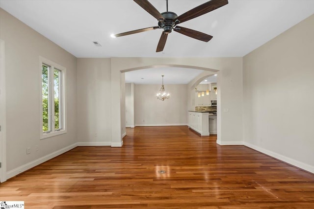 unfurnished living room with ceiling fan with notable chandelier and hardwood / wood-style floors