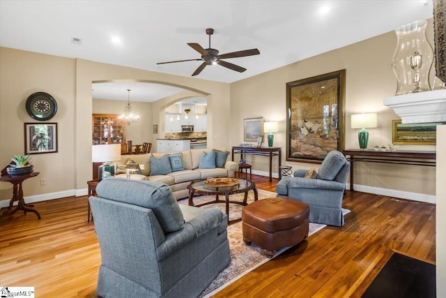 living room featuring ceiling fan with notable chandelier and hardwood / wood-style flooring