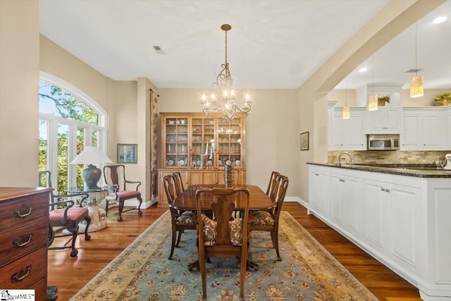 dining space with dark wood-type flooring and a notable chandelier