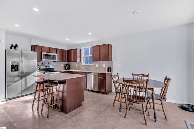 kitchen featuring appliances with stainless steel finishes, tasteful backsplash, a kitchen breakfast bar, a kitchen island, and sink