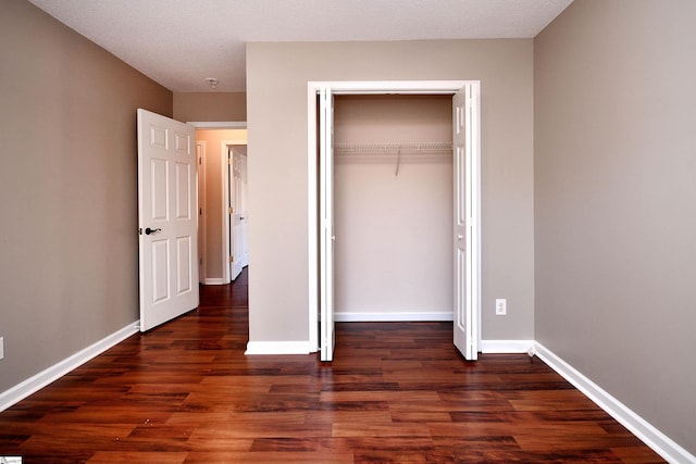 unfurnished bedroom with a closet, dark wood-type flooring, and a textured ceiling