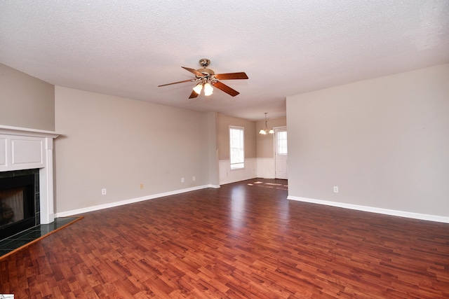 unfurnished living room featuring a textured ceiling, ceiling fan with notable chandelier, and dark hardwood / wood-style floors