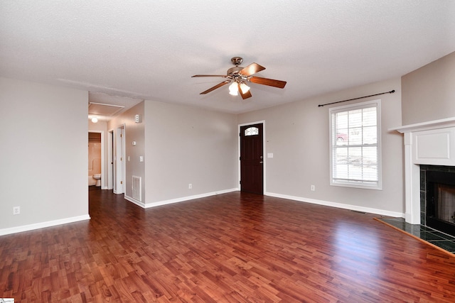 unfurnished living room featuring ceiling fan, a textured ceiling, dark hardwood / wood-style flooring, and a fireplace