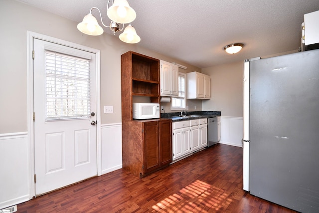 kitchen featuring white cabinetry, stainless steel appliances, an inviting chandelier, sink, and dark hardwood / wood-style floors