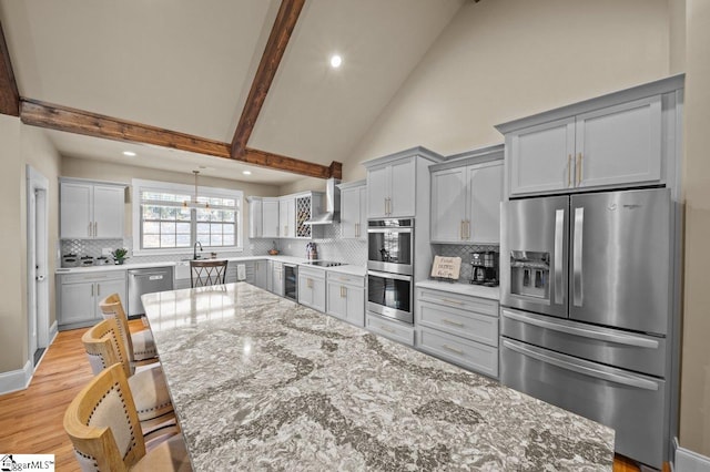 kitchen featuring light stone counters, appliances with stainless steel finishes, gray cabinets, and beam ceiling