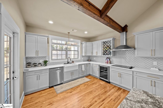 kitchen with beverage cooler, wall chimney range hood, pendant lighting, stainless steel dishwasher, and sink