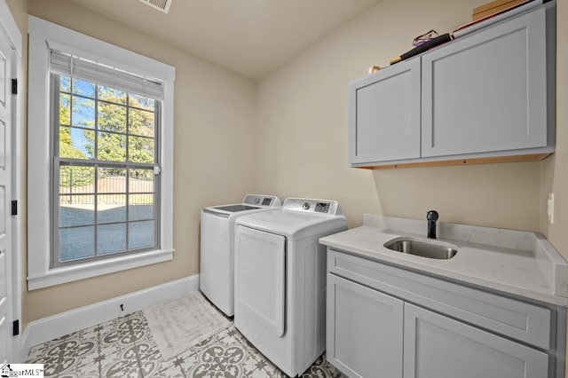 clothes washing area with washer and dryer, light tile patterned flooring, sink, and cabinets