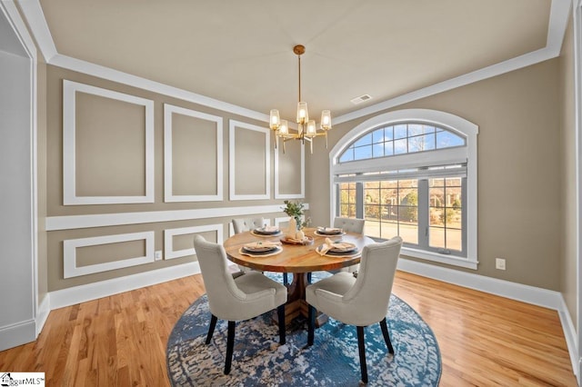 dining space featuring an inviting chandelier, crown molding, and light hardwood / wood-style floors