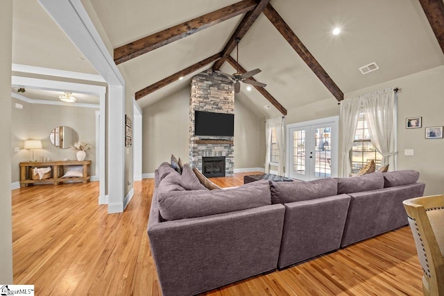 living room with ceiling fan, light hardwood / wood-style flooring, french doors, and a stone fireplace