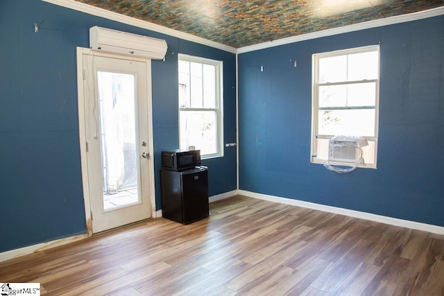 interior space with wood-type flooring, a wall unit AC, cooling unit, and a healthy amount of sunlight