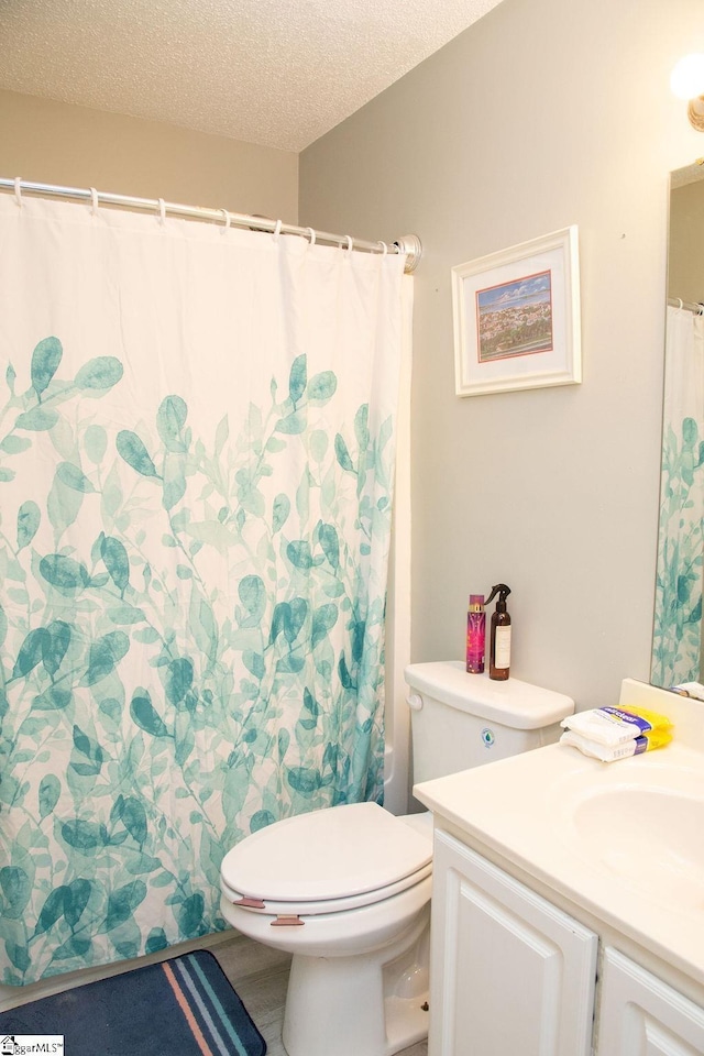 bathroom featuring a textured ceiling, toilet, vanity, and curtained shower