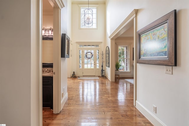 entryway with an inviting chandelier, a wealth of natural light, light hardwood / wood-style flooring, and sink