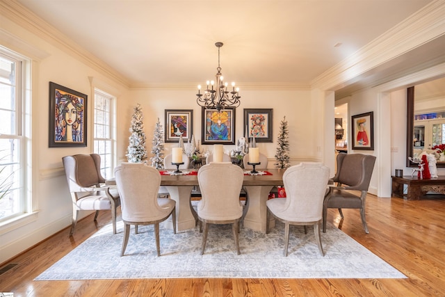 dining space with an inviting chandelier, ornamental molding, and light hardwood / wood-style floors