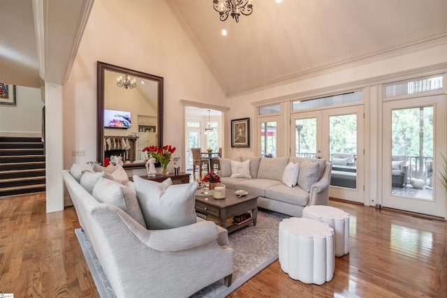 living room with high vaulted ceiling, french doors, a chandelier, and hardwood / wood-style flooring