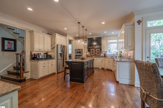 kitchen with a center island, decorative light fixtures, stainless steel appliances, a healthy amount of sunlight, and custom range hood