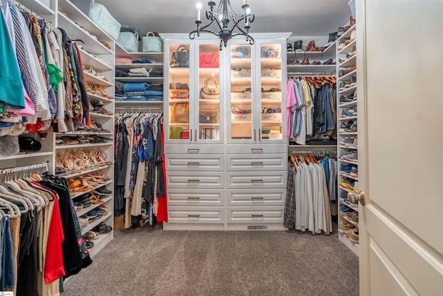 walk in closet with a chandelier and carpet floors