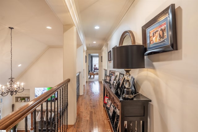 hallway featuring ornamental molding, lofted ceiling, hardwood / wood-style floors, and a notable chandelier