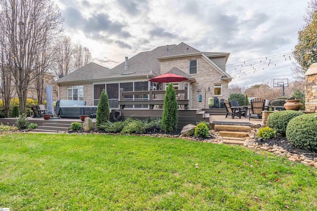 back of property featuring a wooden deck, a sunroom, a yard, a hot tub, and a patio