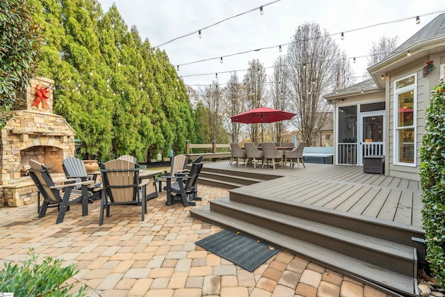 view of patio / terrace featuring a wooden deck, a sunroom, an outdoor stone fireplace, and a fire pit