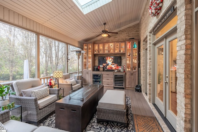 sunroom / solarium with ceiling fan, wine cooler, lofted ceiling with skylight, and wooden ceiling