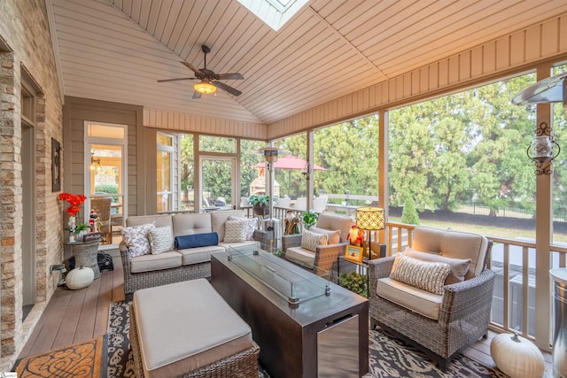 sunroom / solarium featuring ceiling fan, vaulted ceiling with skylight, and wood ceiling