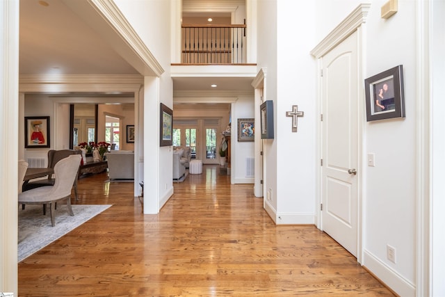 entrance foyer with a high ceiling, wood-type flooring, and ornamental molding