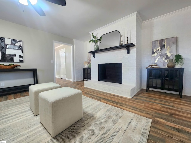 living room with hardwood / wood-style flooring, crown molding, a brick fireplace, and ceiling fan