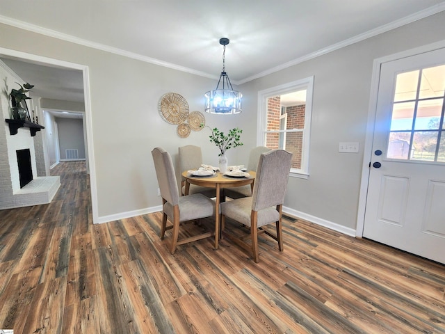 dining area with a brick fireplace, plenty of natural light, ornamental molding, and dark hardwood / wood-style floors