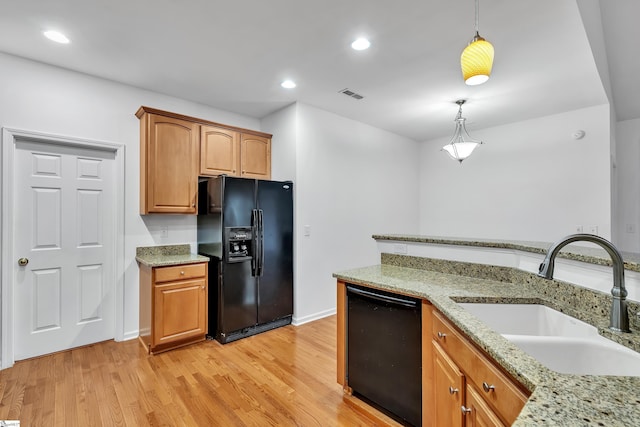 kitchen with light stone countertops, pendant lighting, black appliances, light hardwood / wood-style floors, and sink