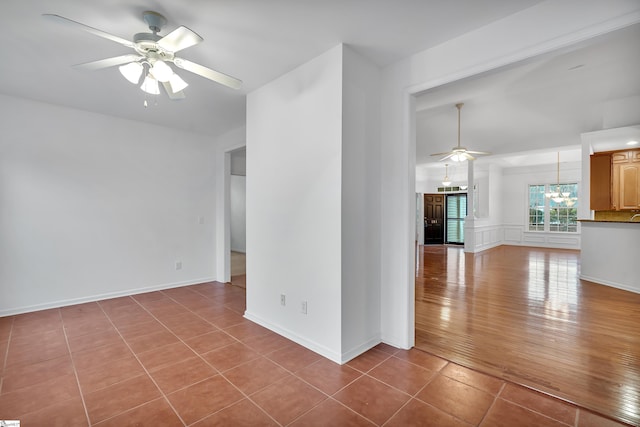 unfurnished room featuring tile patterned floors and ceiling fan with notable chandelier