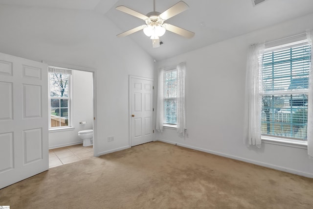 unfurnished bedroom featuring ceiling fan, light colored carpet, lofted ceiling, and ensuite bath