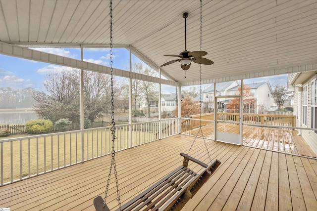 wooden terrace featuring ceiling fan, a lawn, and a water view