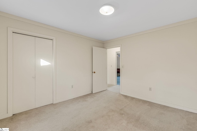 unfurnished bedroom featuring light colored carpet, a closet, and crown molding