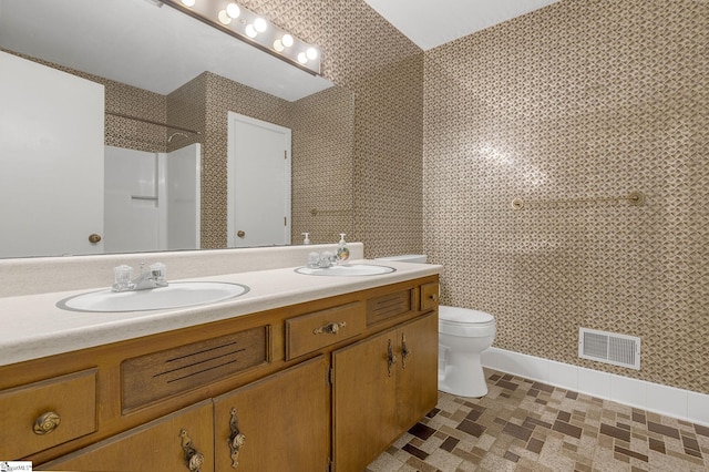 bathroom featuring toilet, vanity, and walk in shower